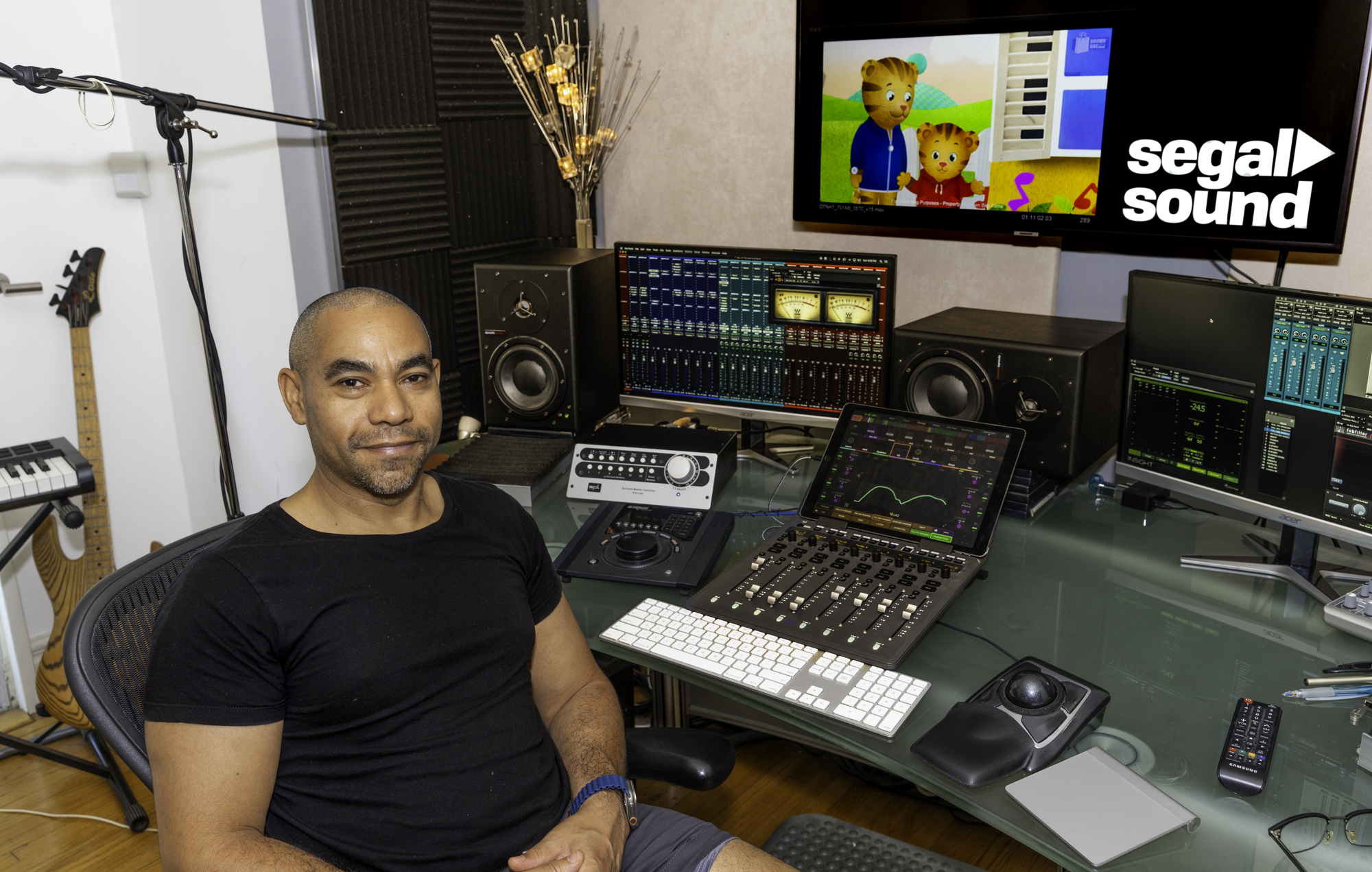 Richard sitting at a sound board. Daniel Tiger on the screen.